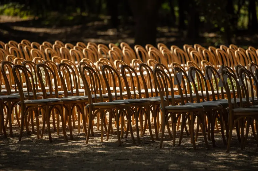 Rangées de chaises en bois dorées installées pour une cérémonie en plein air