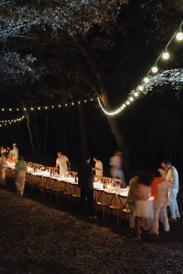 Longue table de dîner éclairée par des guirlandes lumineuses, de nuit