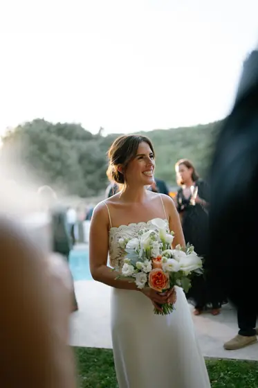 Mariée souriante tenant un bouquet de fleurs blanches et pêche