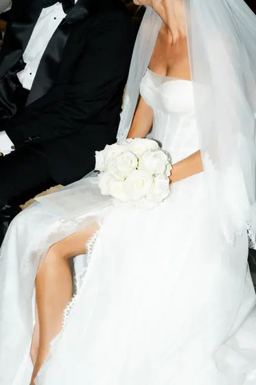 Mariée assise tenant un bouquet de roses blanches