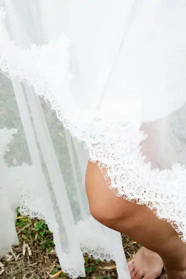 Détail du voile en dentelle de la mariée dans l'herbe
