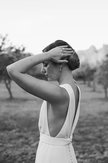Mariée de profil, mains dans les cheveux, robe dos nu