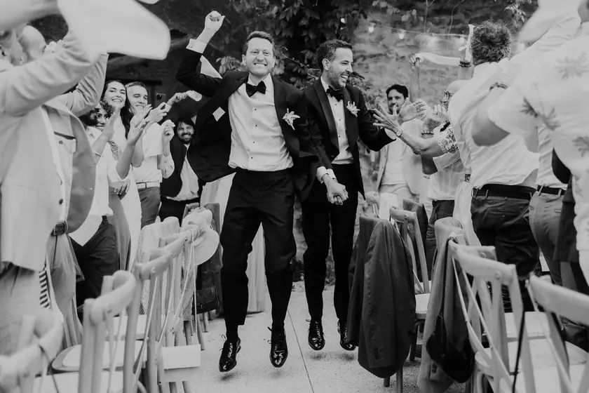 Deux mariés sautant de joie dans l'allée, invités en liesse