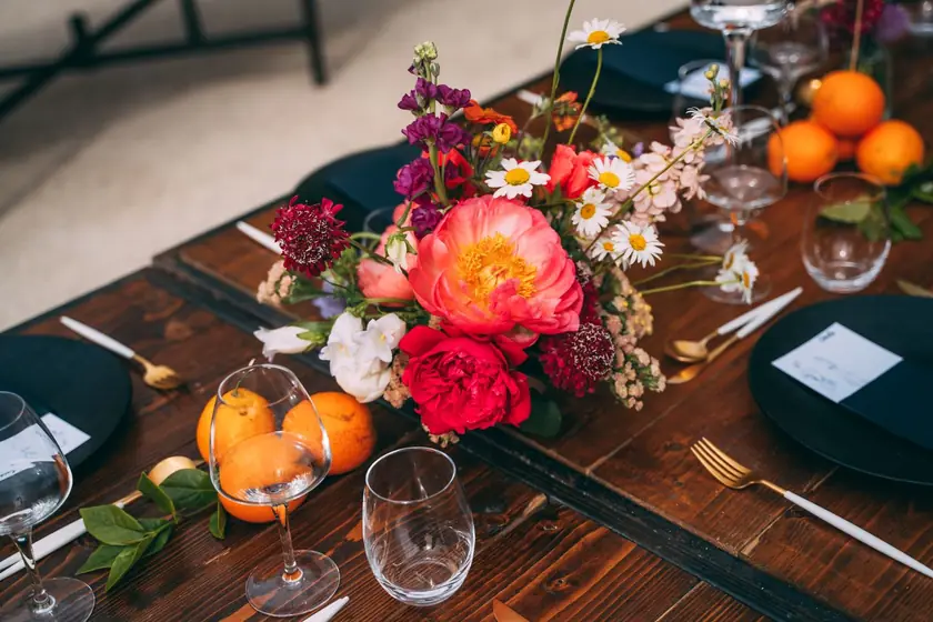 Centre de table de fleurs vives et d'oranges sur une table en bois