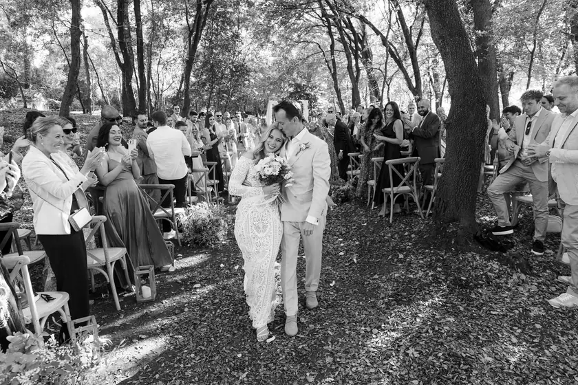 Mariés quittant la cérémonie entre les invités, sous les chênes