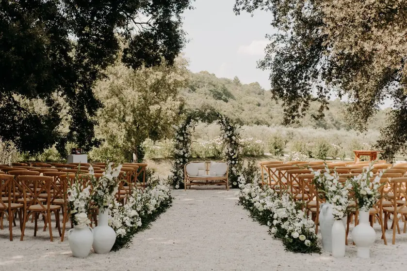 Allée de cérémonie en plein air bordée de chaises et de fleurs blanches