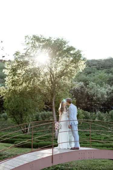 Couple s'embrassant sur un petit pont au milieu des jardins